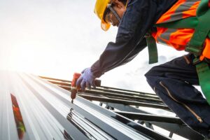 Worker secures a temporary roof tarp while a homeowner observes from a safe distance.